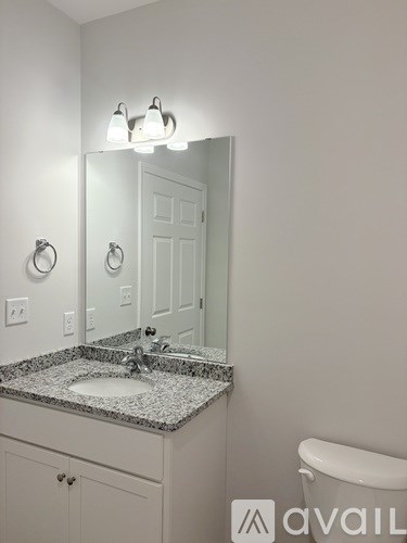 A bathroom with a granite countertop and white fixtures.