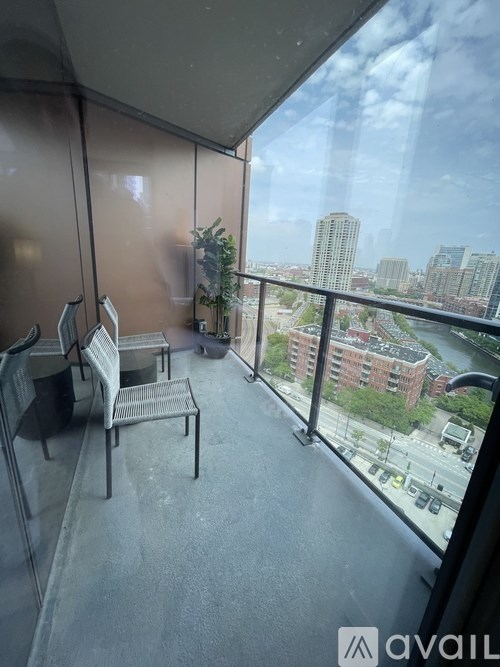 A balcony with a chair and a table overlooking a cityscape.