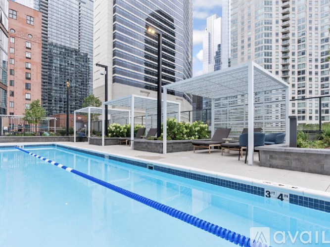 A swimming pool with a blue tiled edge and a white canopy over a seating area.