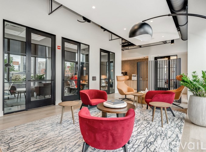 A modern living room with red chairs and a black and white patterned rug.