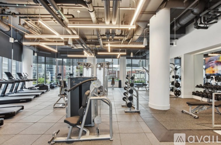 A gym with a variety of equipment including treadmills, weights, and exercise machines.