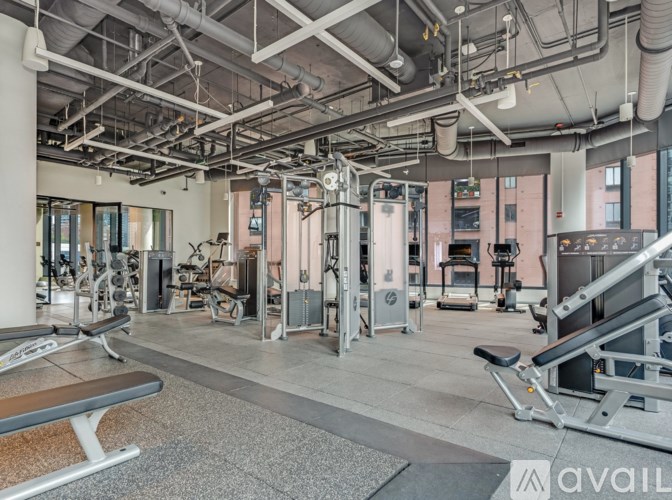 A gym with a variety of equipment including a bench, weights, and a treadmill.