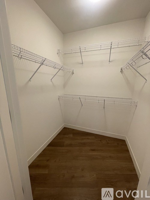 A room with white walls and wooden flooring, equipped with metal wire shelving.