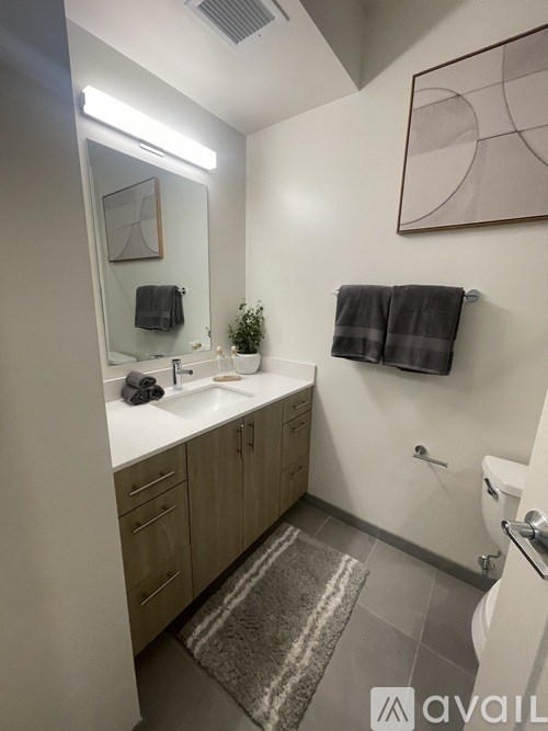 A bathroom with a sink, mirror, towel, and rug.