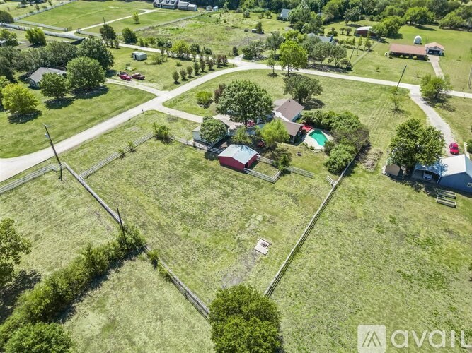 A bird's eye view of a rural area with a few houses and a large open field.