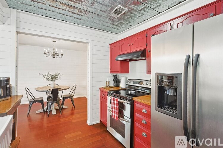 A kitchen with red cabinets and a stainless steel refrigerator.