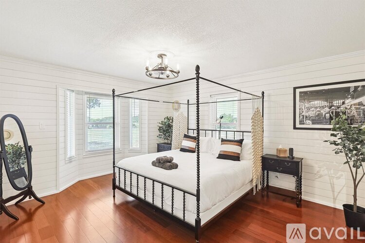 A bedroom with a four-poster bed and a wooden floor.