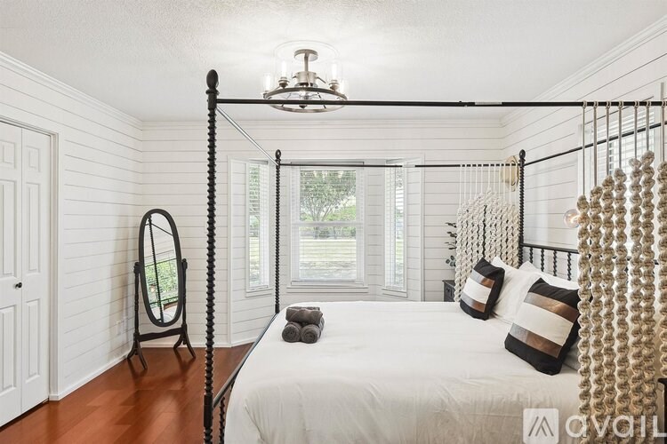 A bedroom with a canopy bed and a mirror on the side table.