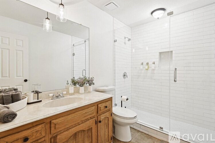 A white bathroom with a toilet, sink, and shower.