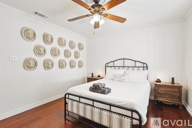 A bedroom with a bed, a ceiling fan, and wall decorations.