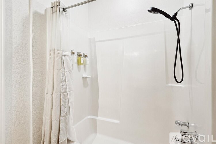 A white bathroom with a shower curtain and a black shower head.