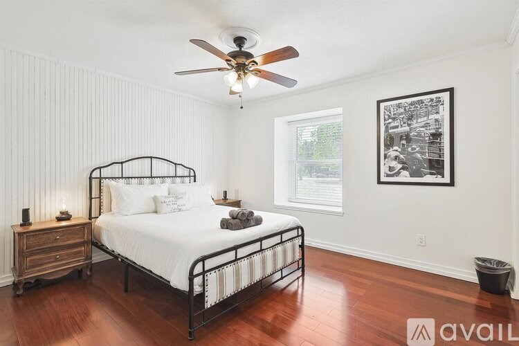 A bedroom with a bed, nightstand, and a ceiling fan.