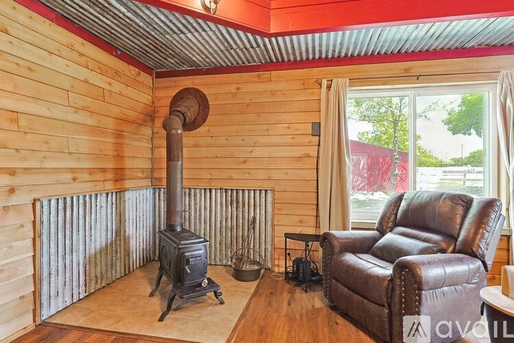 A wood stove in a room with a leather chair.