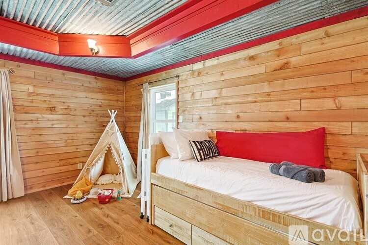 A bedroom with a bed, a teepee, and a window.