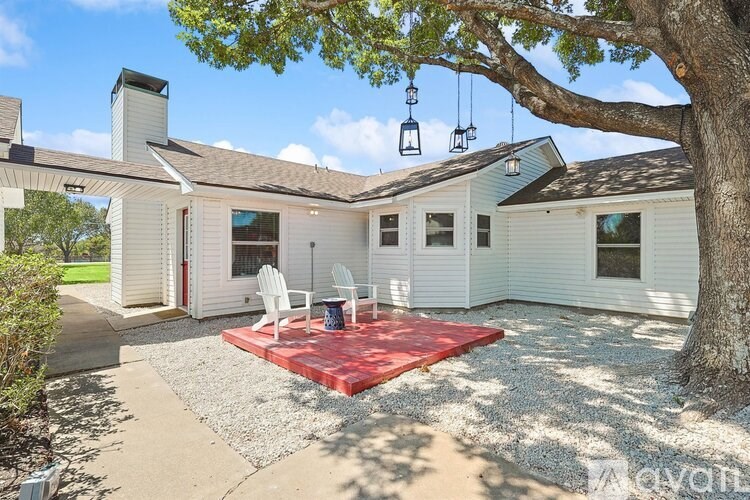 A white house with a red rug in front.