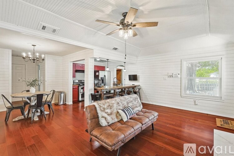 A living room with a brown leather couch and a ceiling fan.