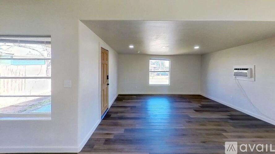 A room with wooden floors and a window showing an outdoor view.