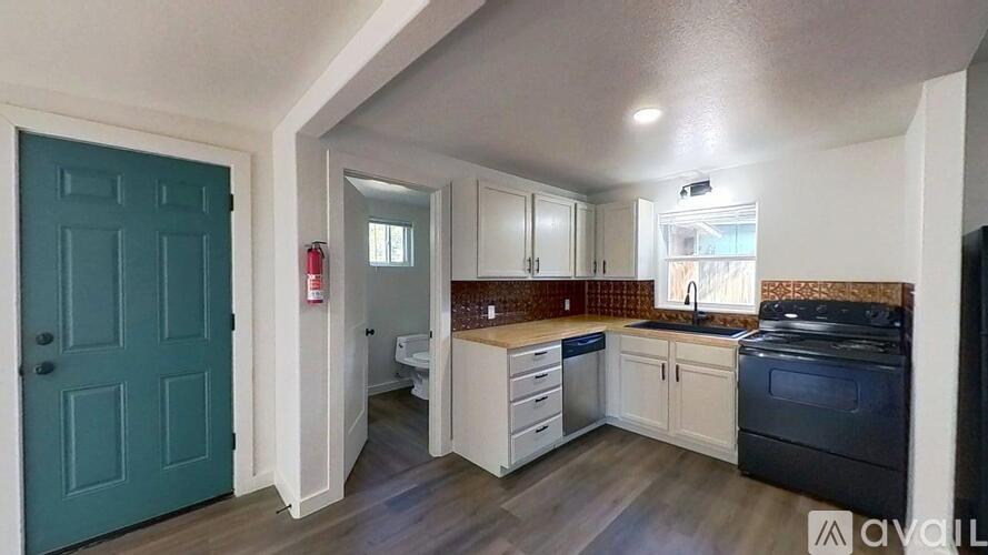 A spacious room with wooden floors and two windows letting in natural light.