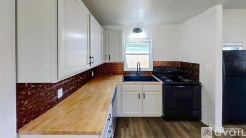 A kitchen with white cabinets and a wooden countertop.