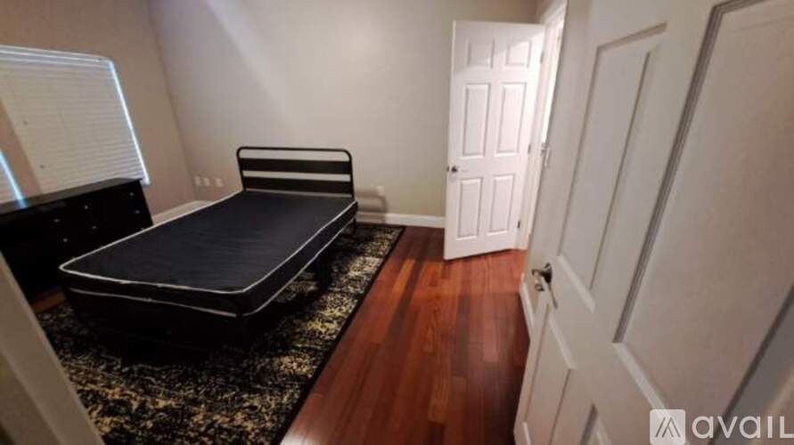 A bedroom with a black bed and a wooden floor.
