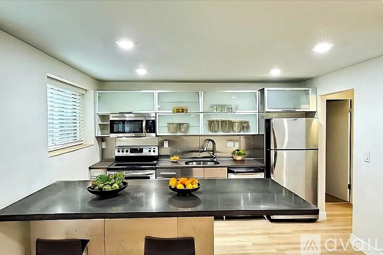A modern kitchen with a black countertop and stainless steel appliances.
