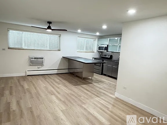 A spacious room with a kitchen area and wooden flooring.
