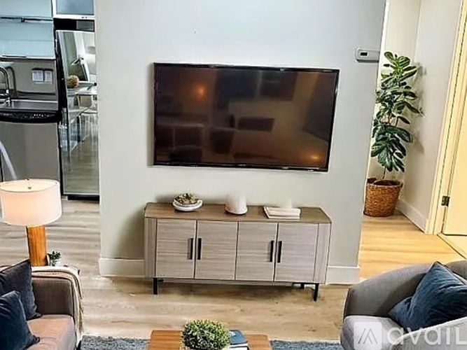 A living room with a flat screen TV mounted on the wall above a cabinet.