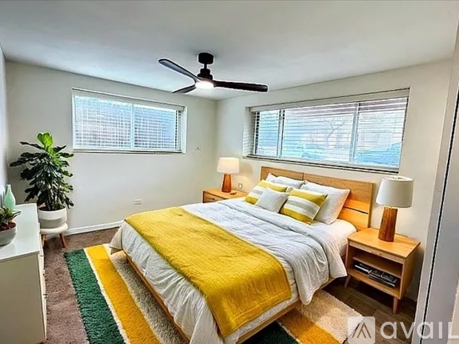 A bedroom with a bed, a ceiling fan, and a window with blinds.