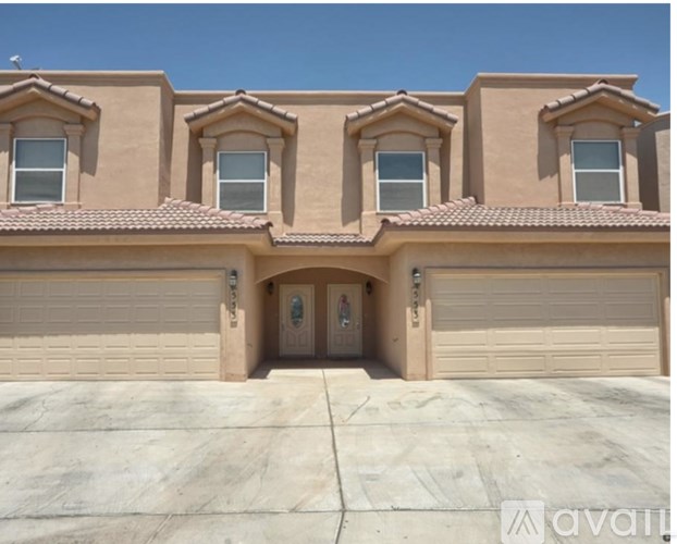 A house with a beige facade and a clear blue sky in the background.