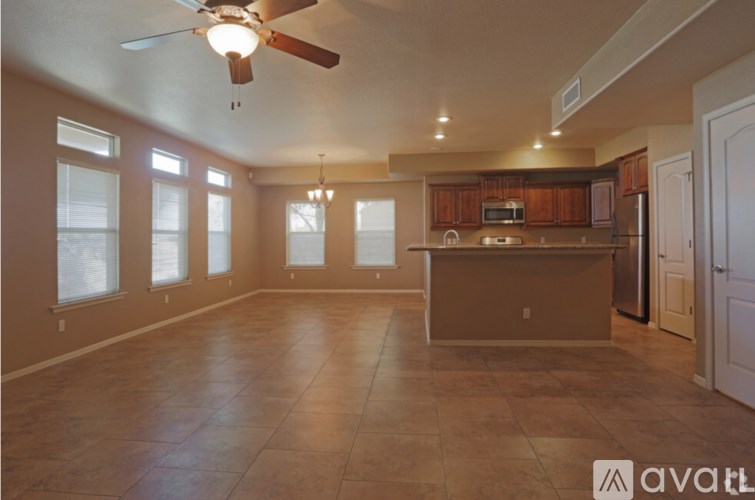 A spacious kitchen and living room with a ceiling fan and tiled flooring.