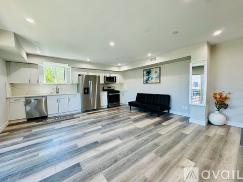 A spacious living room with a kitchen area in the background.