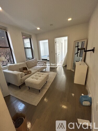 A living room with a white couch and a wooden floor.