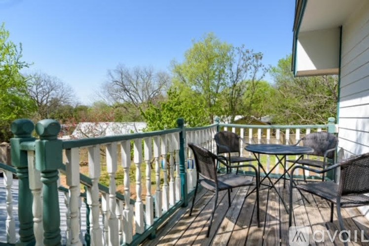 A balcony with a table and chairs overlooking a green landscape.