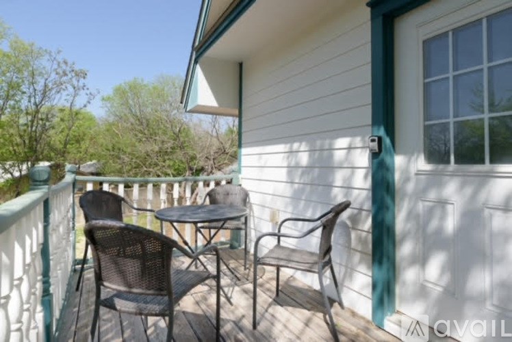 A patio with a table and chairs is on the balcony of a house.