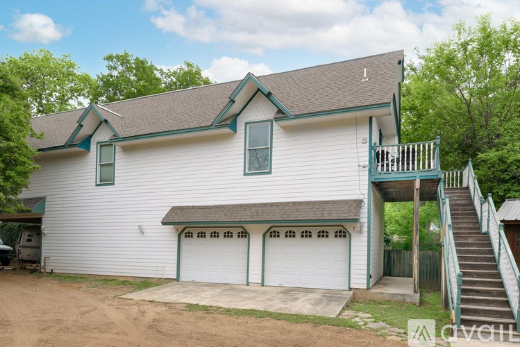 A white house with a green roof and a garage door.