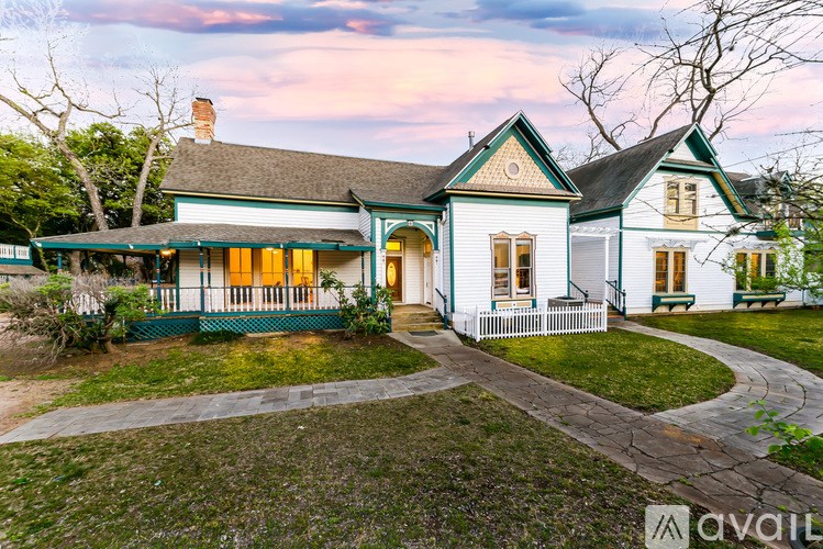 A house with a green front porch and a white picket fence.