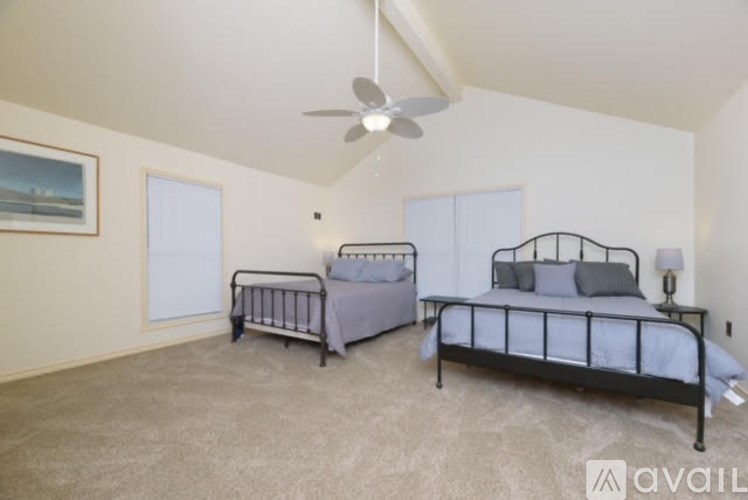 A bedroom with a ceiling fan and two beds.