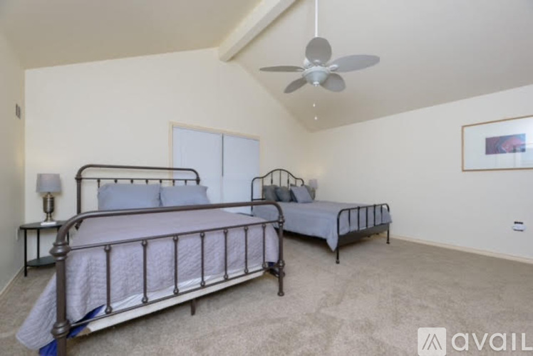 A bedroom with two beds and a ceiling fan.