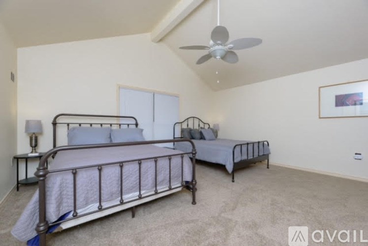 A bedroom with two beds and a ceiling fan.