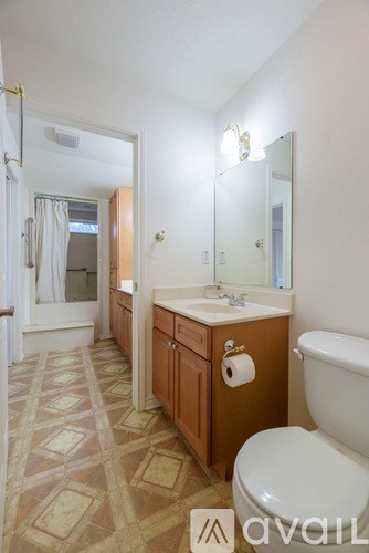 A bathroom with a toilet, sink, and mirror.