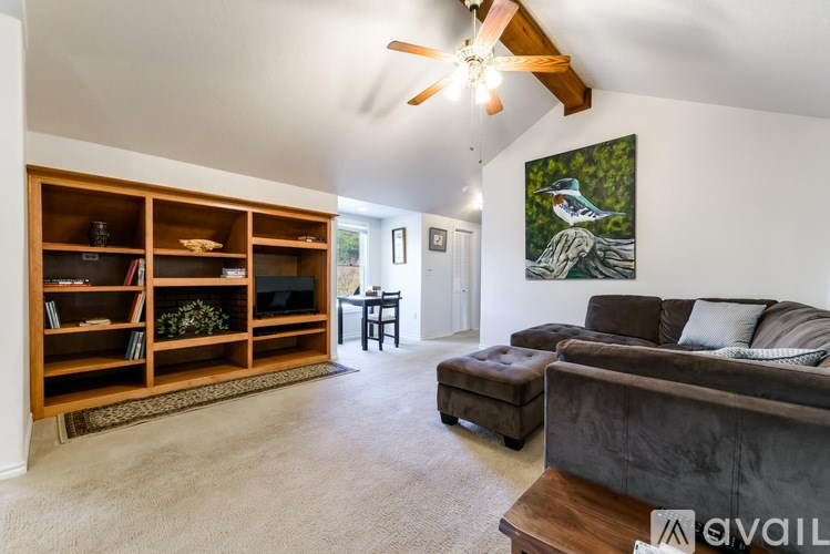 A living room with a couch, a coffee table, a bookshelf, and a painting on the wall.