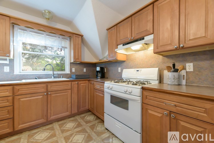 A kitchen with wooden cabinets and a white stove top oven.