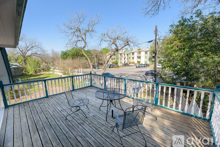 A deck with a table and chairs overlooking a street.