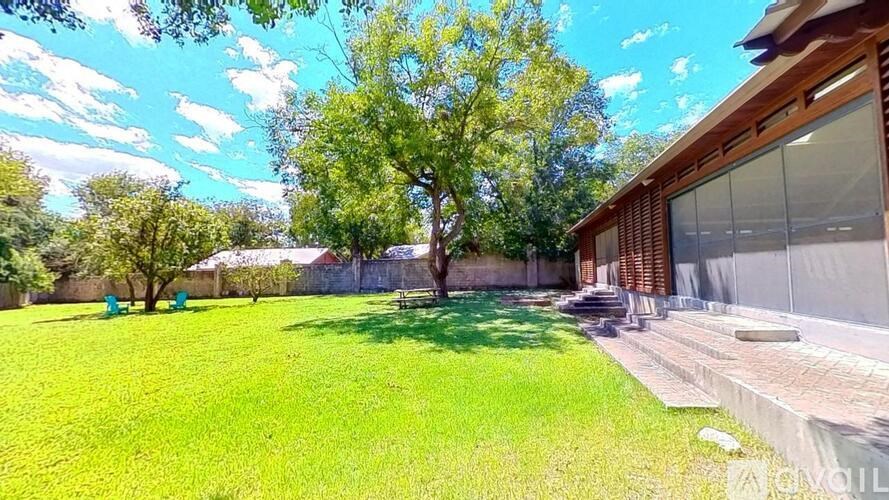 A large grassy area with a tree and a building in the background.