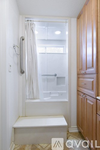 A bathroom with a white tub and wooden cabinets.