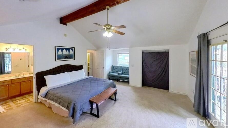 A bedroom with a bed, a bench, and a ceiling fan.