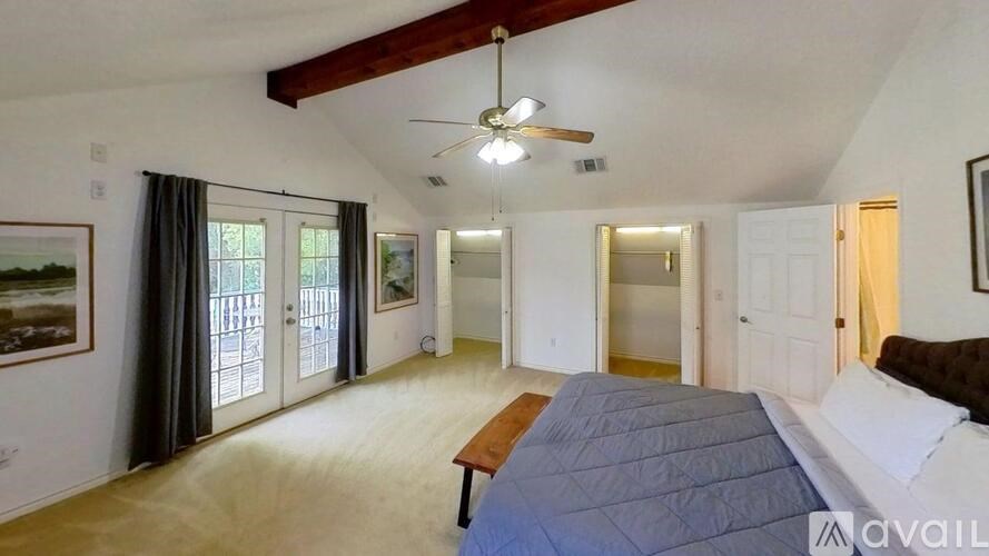 A bedroom with a bed, a ceiling fan, and a painting on the wall.