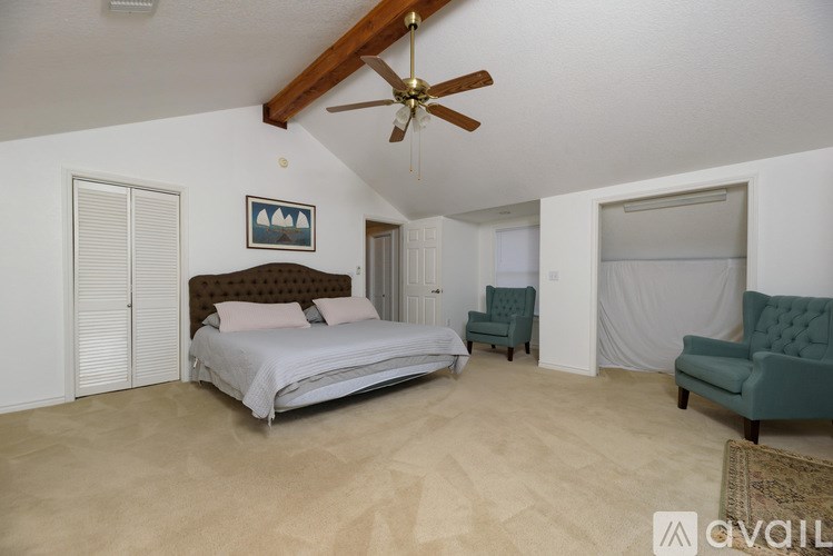 A bedroom with a bed, chair, and a ceiling fan.