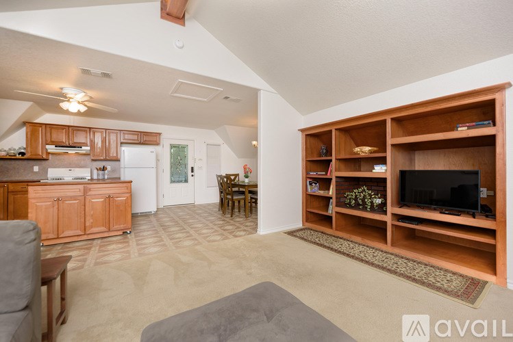 A living room with a grey couch and a wooden entertainment center.
