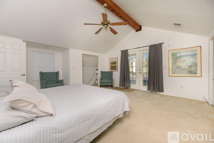 A bedroom with a large bed and a ceiling fan.